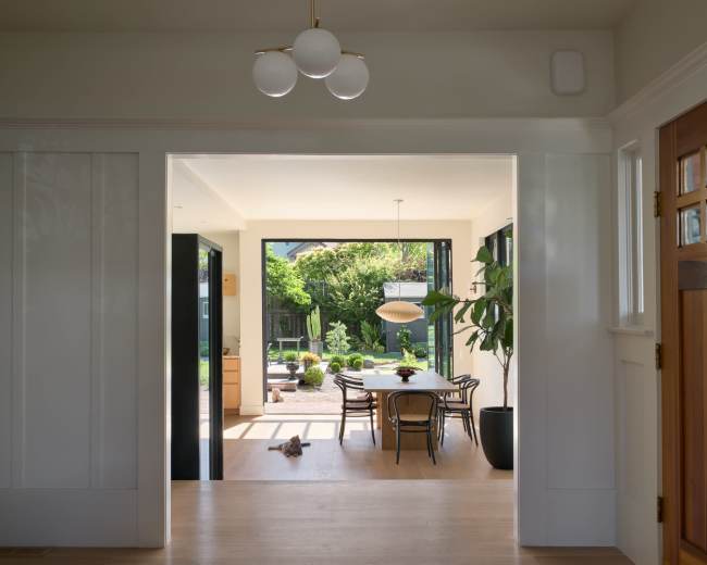 A bright, modern entryway leads to a dining area that opens up to a garden patio.