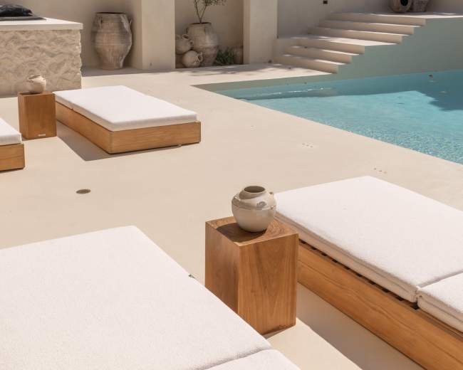 The image features a modern outdoor pool area with minimalist lounge chairs, wooden accents, and a landscaped background.