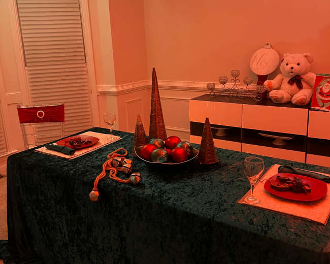 A dining table is set with decorative items, including a bowl of fruit and cone-shaped centerpieces, in a softly lit room.