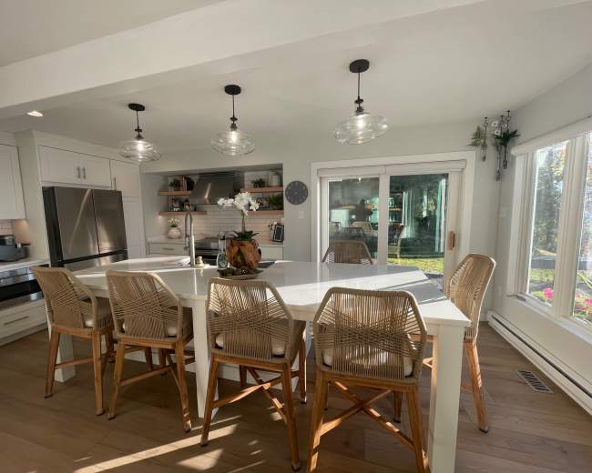 A modern kitchen features a large island with seating for six, stainless steel appliances, and large sliding glass doors leading to an outdoor area.