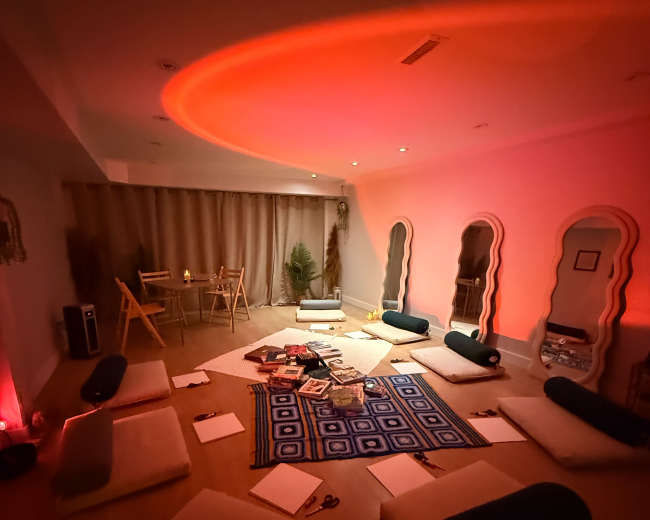 A meditation or wellness space features floor cushions arranged around a central rug, with soft lighting creating a warm ambiance.