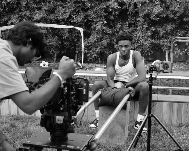A filmmaker captures a seated subject on a playground set while preparing for a shoot.