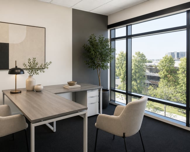 The image depicts a modern office space featuring a minimalist desk, two upholstered chairs, a lamp, and large windows overlooking a green landscape.