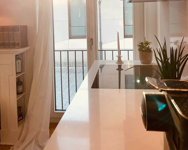 A sunbeam streams through a window, illuminating a kitchen countertop with a candle and potted plant.