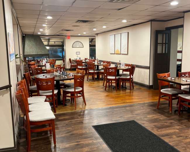 The image shows a restaurant interior with multiple tables arranged in a spacious layout, featuring wooden floors and traditional furnishings.