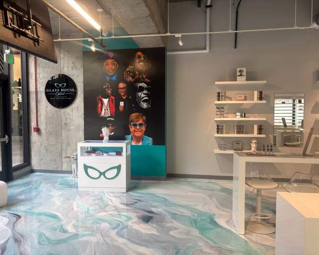 The image shows a modern retail space featuring a colorful mural of various faces on the wall, a display counter with a unique design, and minimalist shelving units.