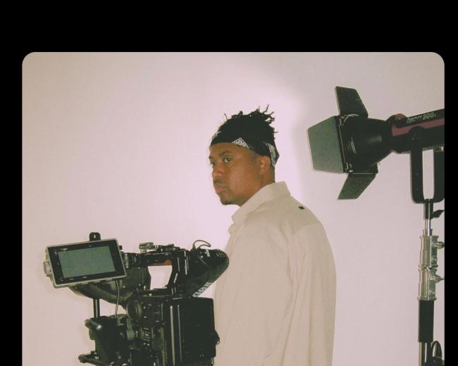 A person stands in front of a camera setup in a studio environment.