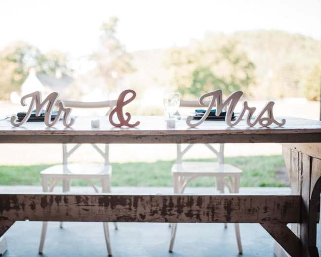A wooden table set for two with "Mr" and "Mrs" signs prominently displayed.