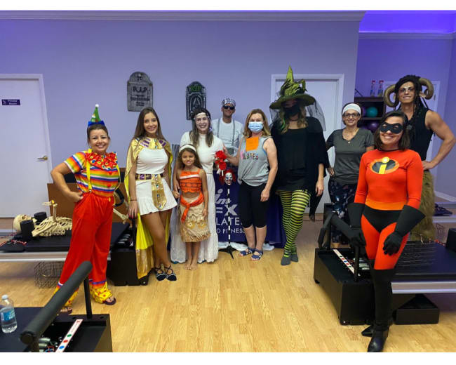 A group of people in costumes poses together in a fitness studio.