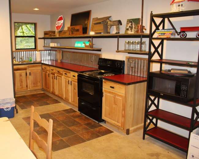 The image shows a kitchen with wooden cabinetry, a black stove, red countertops, and a combination of open and closed shelving.