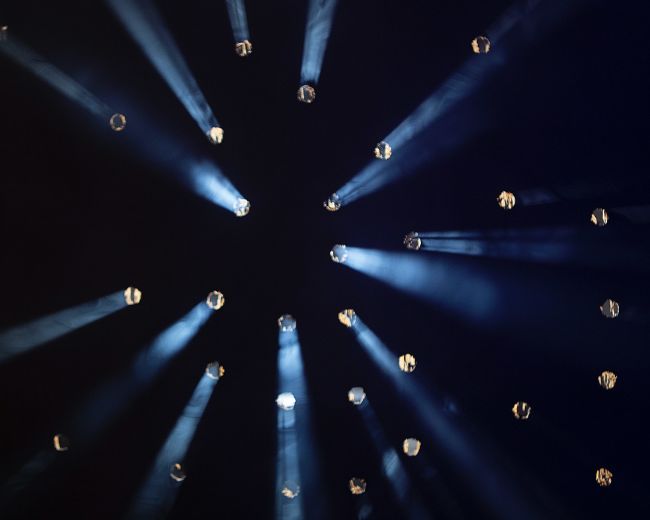 Light beams radiate from various points against a dark background, creating a star-like effect.