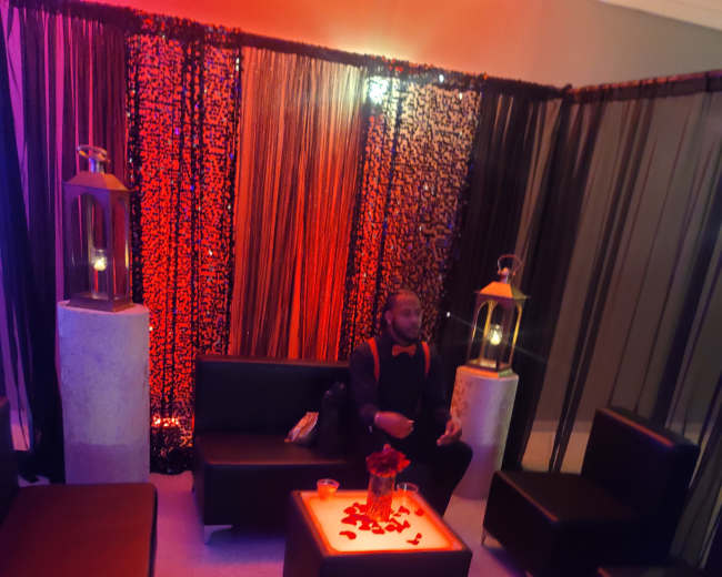 The scene features dimly lit seating with black furniture and decorative lanterns, creating a cozy atmosphere.