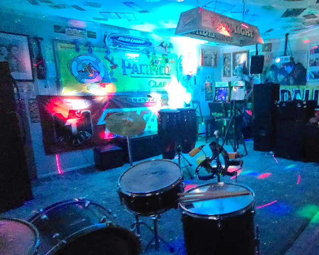 A lively room filled with musical instruments, colorful lighting, and various posters and decorations on the walls.