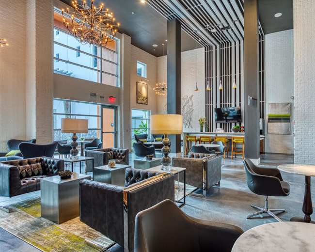 The image shows a modern lobby with stylish furniture, large windows, and contemporary lighting fixtures.