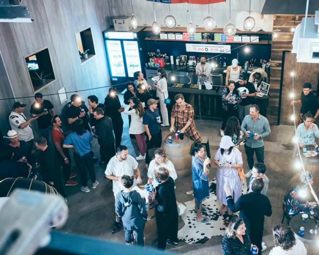 A crowded bar scene features people mingling, socializing, and enjoying drinks in a lively atmosphere.