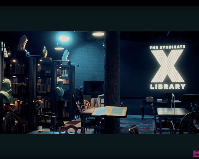 The image shows a dimly lit library with dark bookshelves, a large illuminated sign reading "THE SYNDICATE X LIBRARY," and various sculptures displayed on top of the shelves.