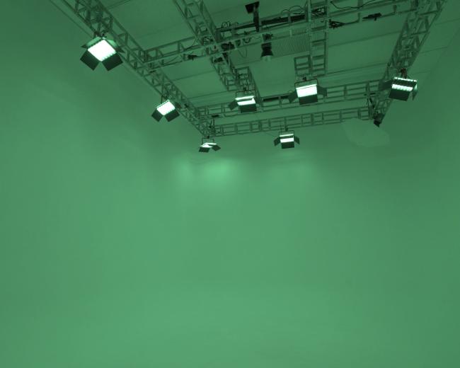 A green screen studio with overhead lighting fixtures.