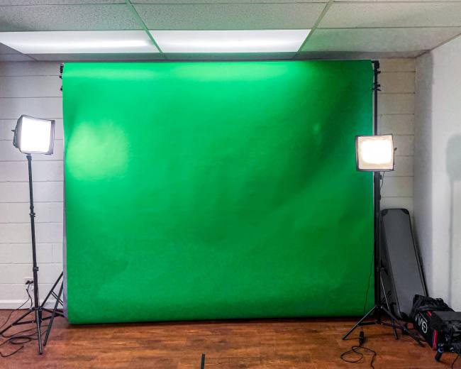 A green screen setup in a well-lit room with two studio lights positioned on either side.