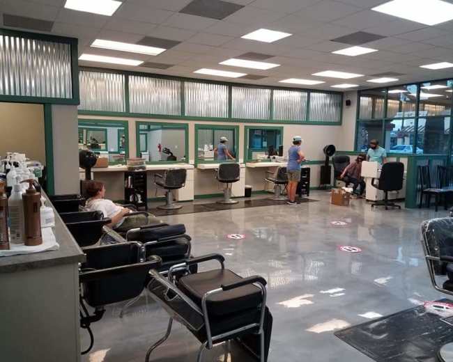 The image depicts a hair salon with several styling stations, salon chairs, and customers being attended to by stylists.