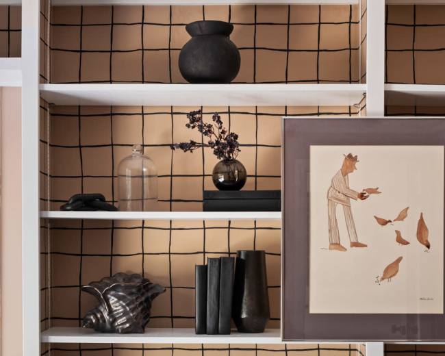 A modern shelving unit displays a variety of decorative items, including vases, books, and artwork, against a grid-patterned background.
