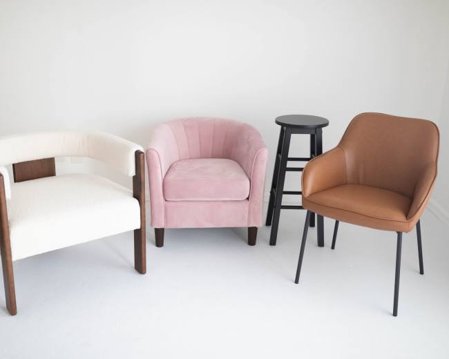 The image shows four chairs arranged in a minimalist setting with a white background.
