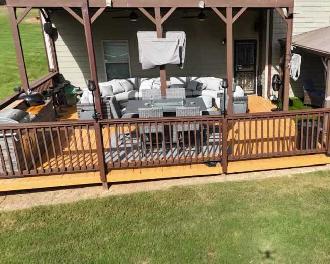 A wooden deck features a well-furnished seating area and a gazebo, surrounded by a grassy lawn.
