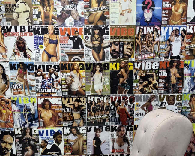 The image features a high-heeled chair positioned against a wall covered with various magazine covers, predominantly showcasing models.