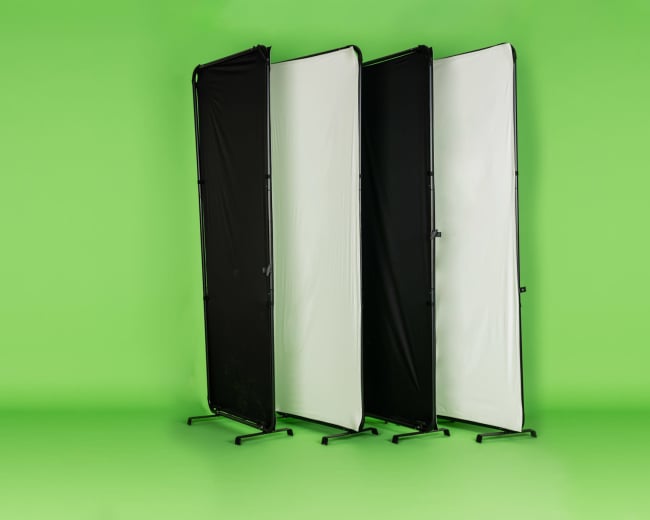 The image shows three portable backdrop panels in black, white, and gray arranged against a bright green background.