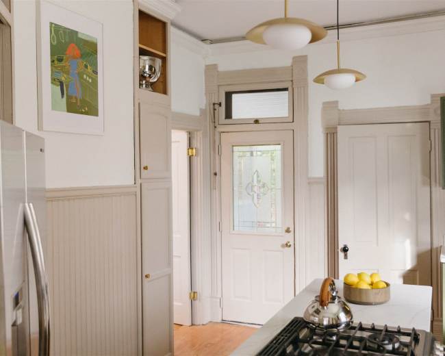 A bright kitchen with light-colored walls, a glass door, and a bowl of lemons on the countertop.