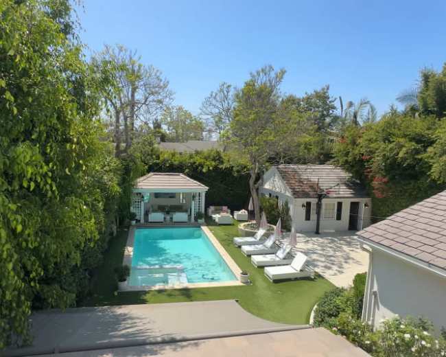 The image shows a residential backyard featuring a swimming pool, several lounge chairs, a gazebo, and landscaped greenery.