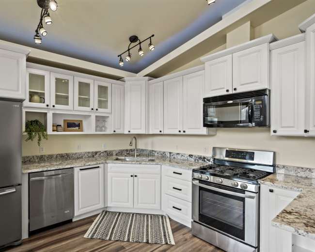 A modern kitchen featuring white cabinetry, stainless steel appliances, and a granite countertop.