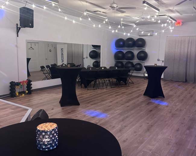 The room features black tables, string lights overhead, and exercise balls arranged against a wall.