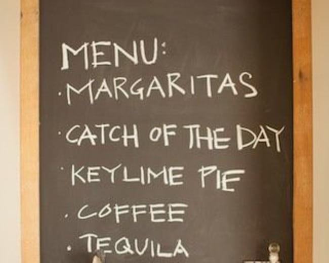 A chalkboard menu displays "Margaritas," "Catch of the Day," "Key Lime Pie," "Coffee," and "Tequila" in a kitchen setting.