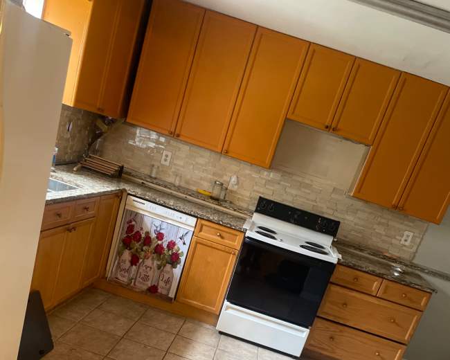 The image shows a kitchen with orange cabinets, a white stove, and tiled flooring.