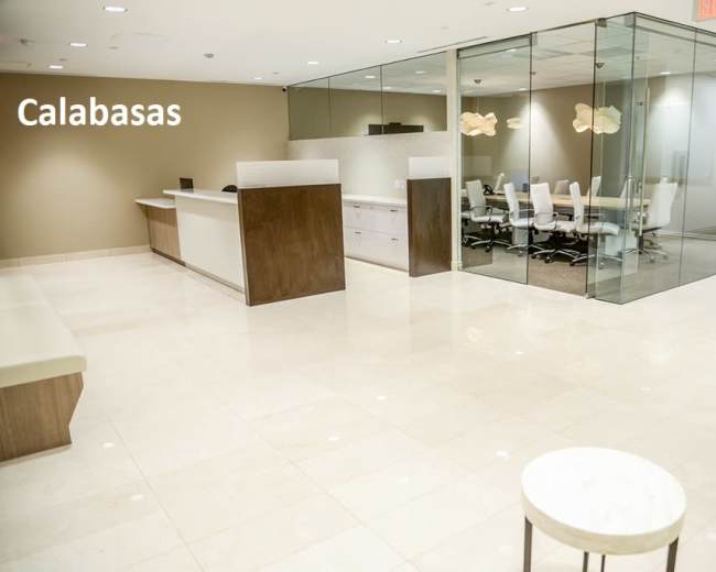 A modern office reception area with a front desk and a glass-enclosed conference room.