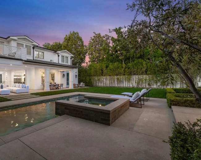 The image shows a modern two-story house with a swimming pool and outdoor seating area, set against a colorful evening sky.