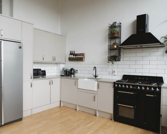 The kitchen features stainless steel appliances, light-colored cabinetry, and a gas range with a black hood.