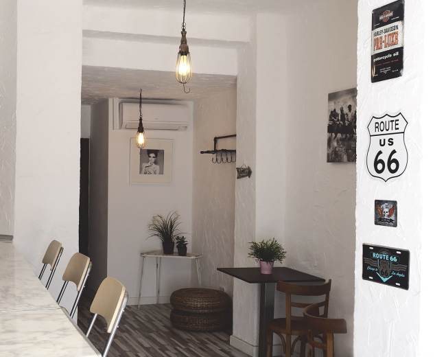 The image shows a modern, minimalist café interior with a marble counter, wooden seating, and decorative elements on the walls.