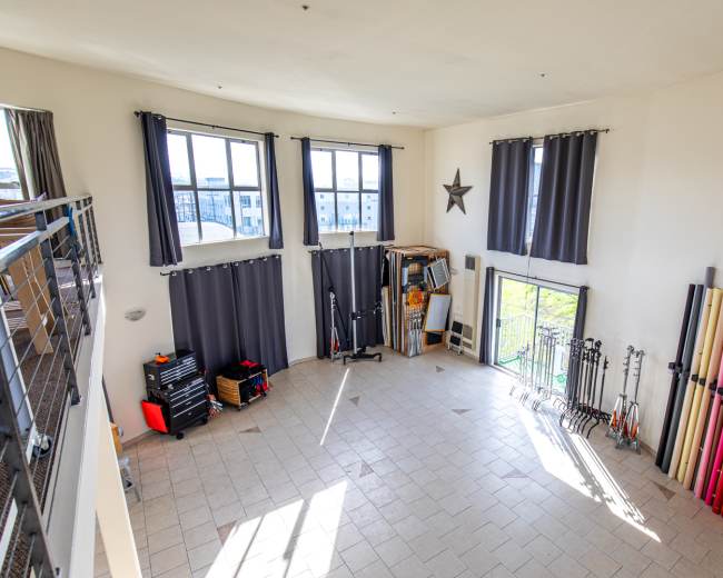 The spacious room features large windows, gray curtains, and colorful backdrops arranged along one wall.