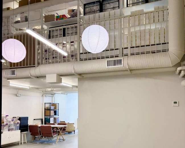 The image shows a modern office space with a lofted area and two hanging round light fixtures.