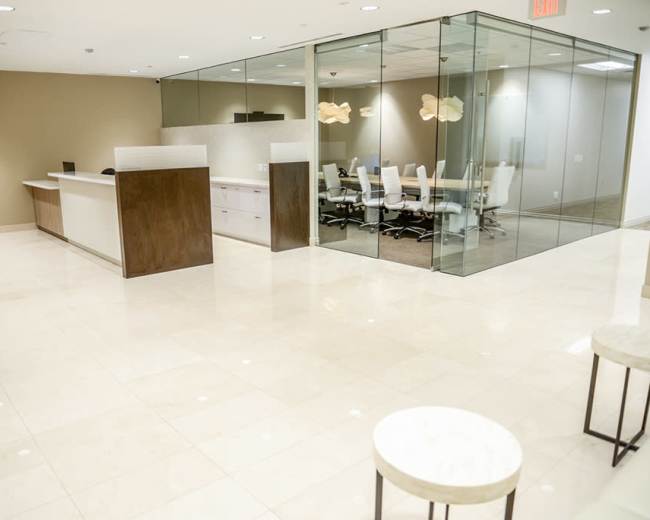 A modern office lobby features white tiled flooring, a reception desk, and a glass conference room with a table and chairs.