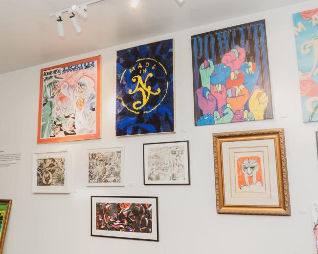A gallery wall featuring various framed artworks with vibrant colors and different artistic styles.
