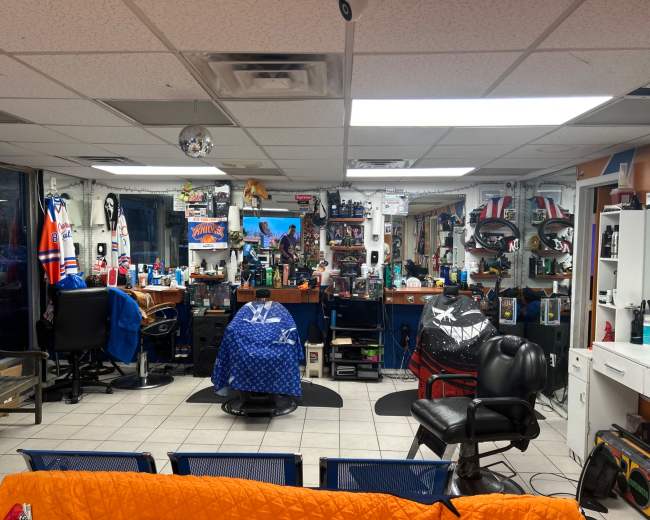 The interior of a barbershop features multiple styling stations, barbershop chairs, and various grooming products displayed on shelves.