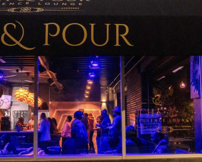 The image shows a lively lounge scene with patrons socializing under dim lighting and blue accents.