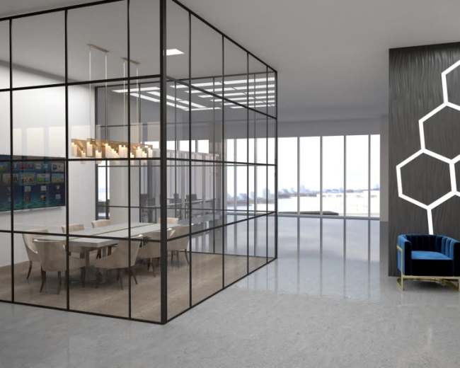 The image shows a modern office space featuring a glass-walled conference room, a sleek media wall, and two blue armchairs against a geometric patterned accent wall.