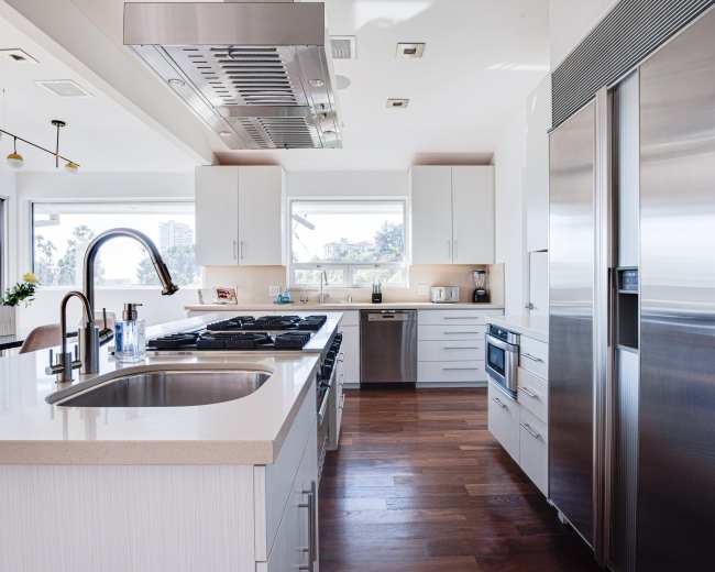 A modern kitchen with a central island, stainless steel appliances, and large windows providing ample natural light.