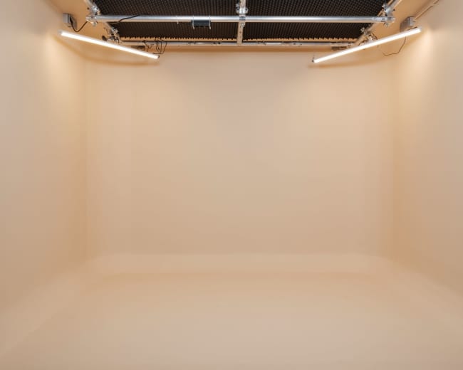The image shows a clean, empty room with beige walls and ceiling lights.