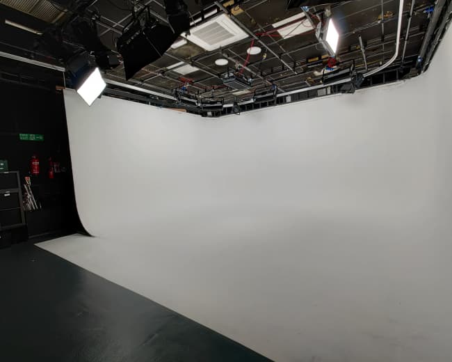 A studio space with a seamless white backdrop and overhead lighting setup.