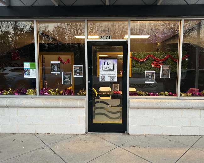 The image shows the entrance of a storefront decorated with colorful garlands and promotional posters in the windows.