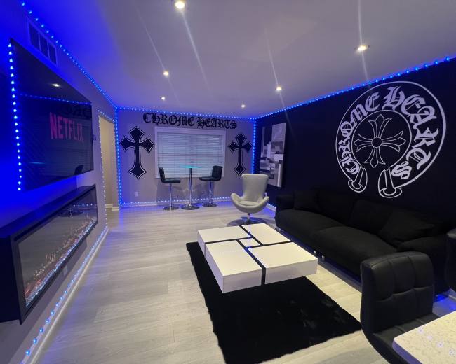 The room features a modern design with black and white furniture, neon blue lighting, and decorative wall art.